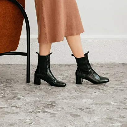 Heeled boots with gathers in black aged leather